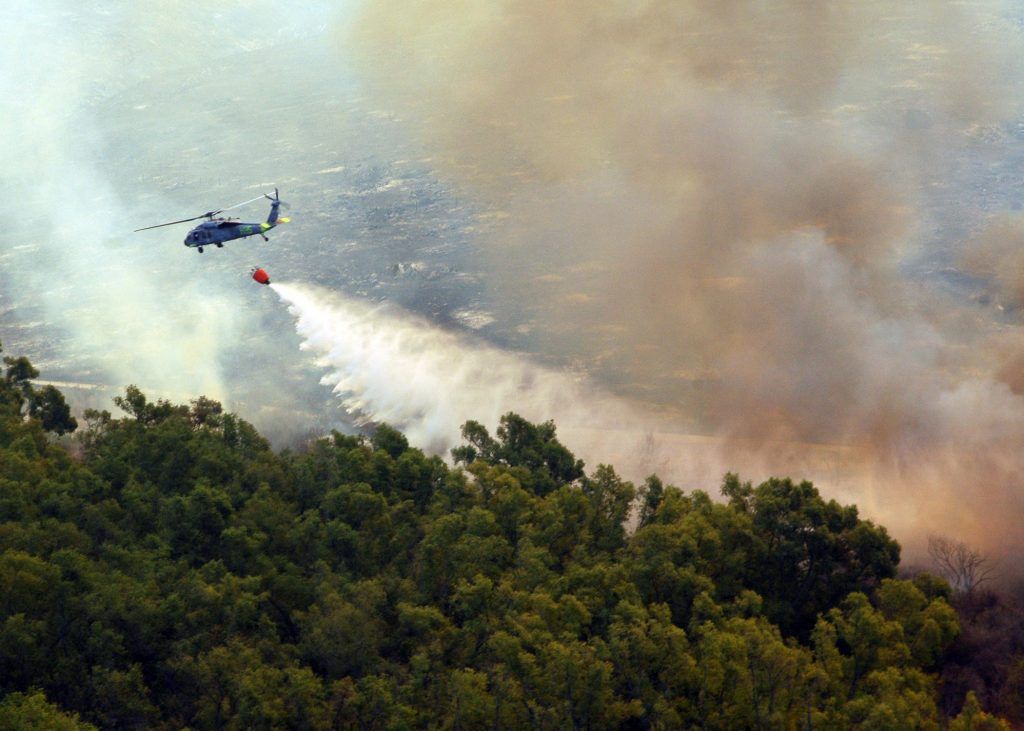 An MH-60S Seahawk helicopter assigned to Helicopter Sea Combat Squadron (HSC) Eight Five dumps water from a 420-gallon extinguishing trough Oct. 23, 2007, onto of one of the many areas in San Diego County, Calif., suffering from an ongoing wildfire. The trough is used to dump water to help fend off the fires that have already forced more than 250,000 people from their homes. DoD photo by Mass Communication Specialist 2nd Class Chris Fahey, U.S. Navy. (Released)