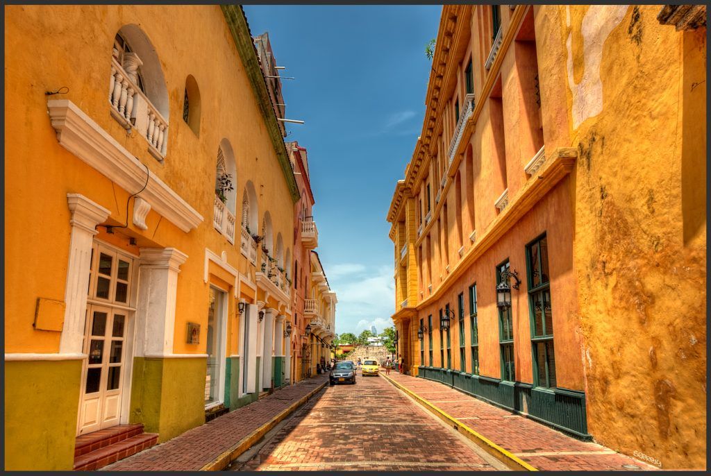 Cartagena has many yellow bulidings. This one is a fine example. Very typical of Cartagena. HDR of three handheld shots. Processed using Photomatix 4 beta details enhancer. Used the manual ghost removal on the approaching cars. Photomatix allowed me to brighten the buildings while retaining detail in the sky. Used PS lens correction to straighten the verticals a bit, then Nik Pro Contrast and a bit of Tonal Contrast. Used Nik Polarizer, as I don't have a real polarizer for my 10-22mm. Burned the street, and did a bit of Nik Darken/Lighten center to darken the edges.